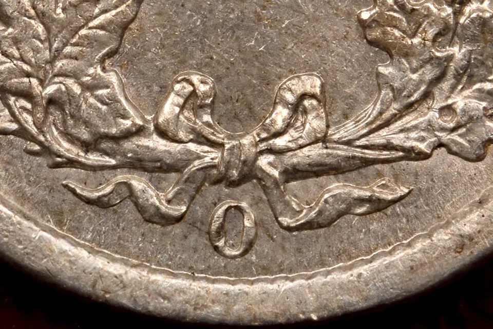 how much is a Barber dime worth — extreme macro of the small O mint mark below the wreath bow on an 1895-O Barber dime