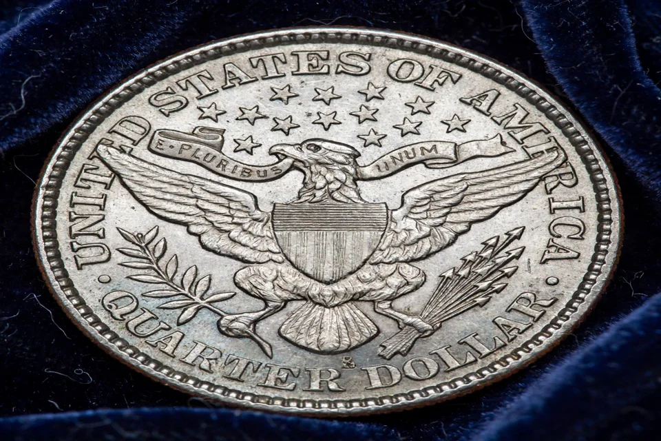 Barber quarter reverse close-up — heraldic eagle with outstretched wings, shield on its breast, and QUARTER DOLLAR below