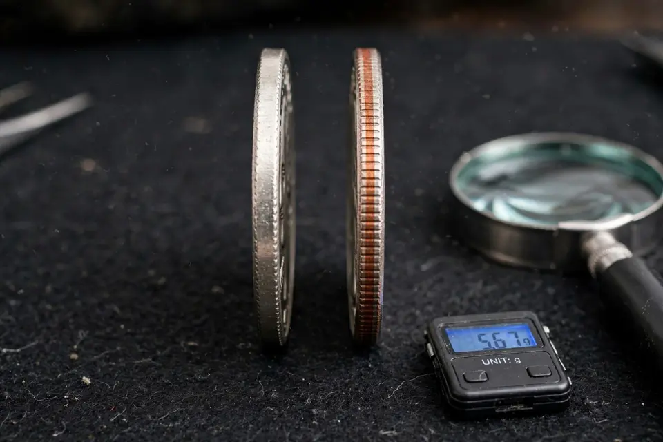 Bicentennial quarter edge comparison — solid silver edge versus clad edge with a copper stripe, with magnifier and scale
