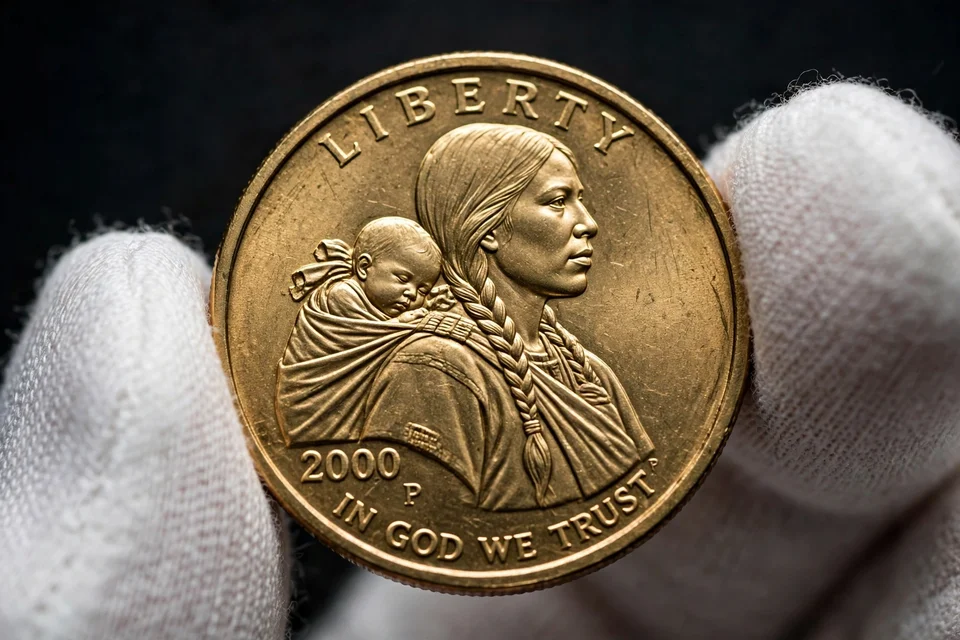 golden Sacagawea dollar obverse close-up — 2000 date and P mint mark in cotton gloves