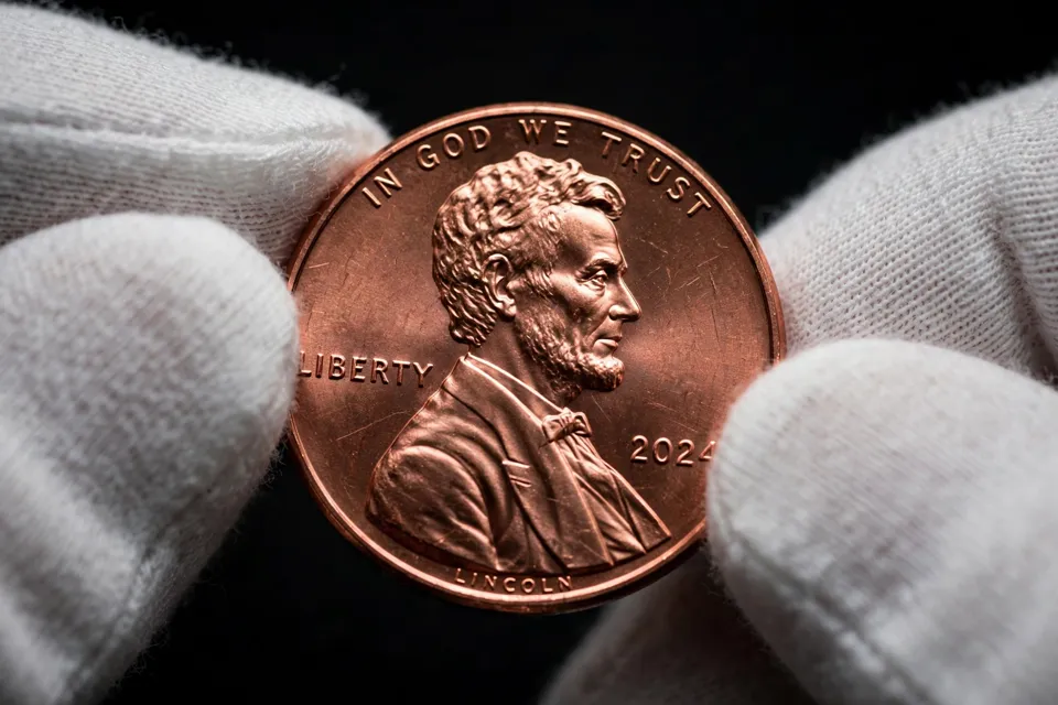 Lincoln cent obverse close-up in cotton gloves — 2024 date, LIBERTY and IN GOD WE TRUST